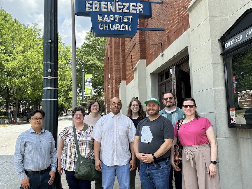 Group of people standing in front of a building under a sign that says Ebenezer Baptist Church.