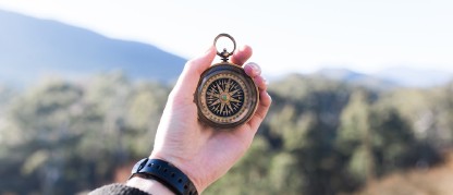 hand extended holding a compass outdoors