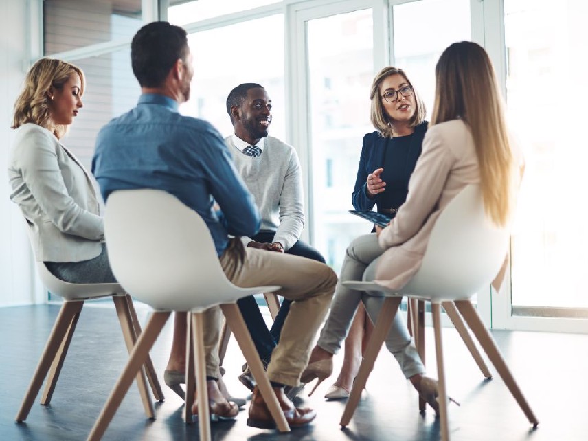 A group of people sitting in chairs having a conversation