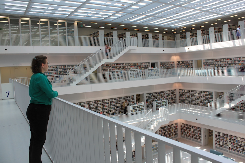 Myka Kennedy Stephens standing on the seventh floor of the Stadtbibliothek Stuttgart overlooking the open atrium and four floors of library bookstacks.